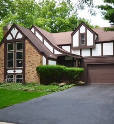 two story brown and white tudor style home with brown windows