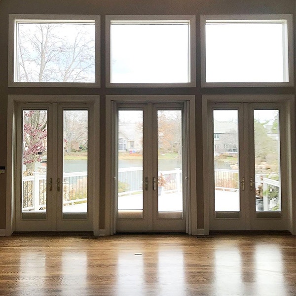 Three hinged doors with large fixed windows over each creates a wall of glass.