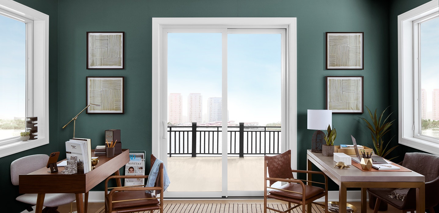 Green office space with two desks and white sliding door to city view