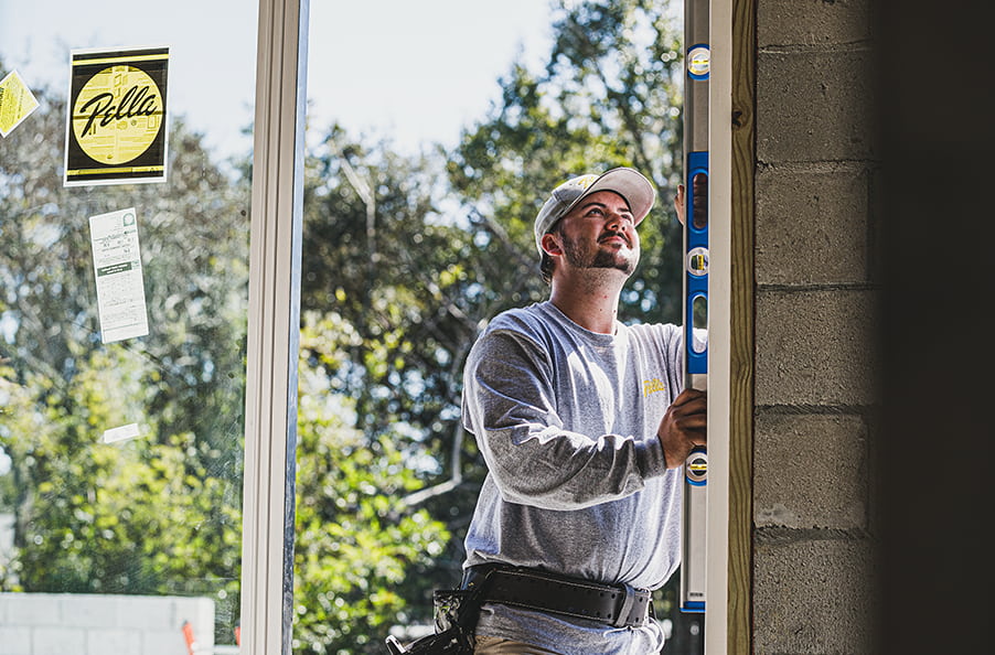 a contractor is using a level to ensure the new patio door is correctly positioned