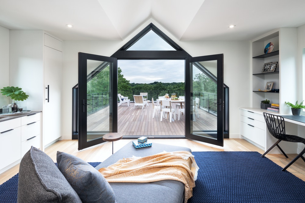 black french doors paired with special shape windows create triangle entryway to backyard patio