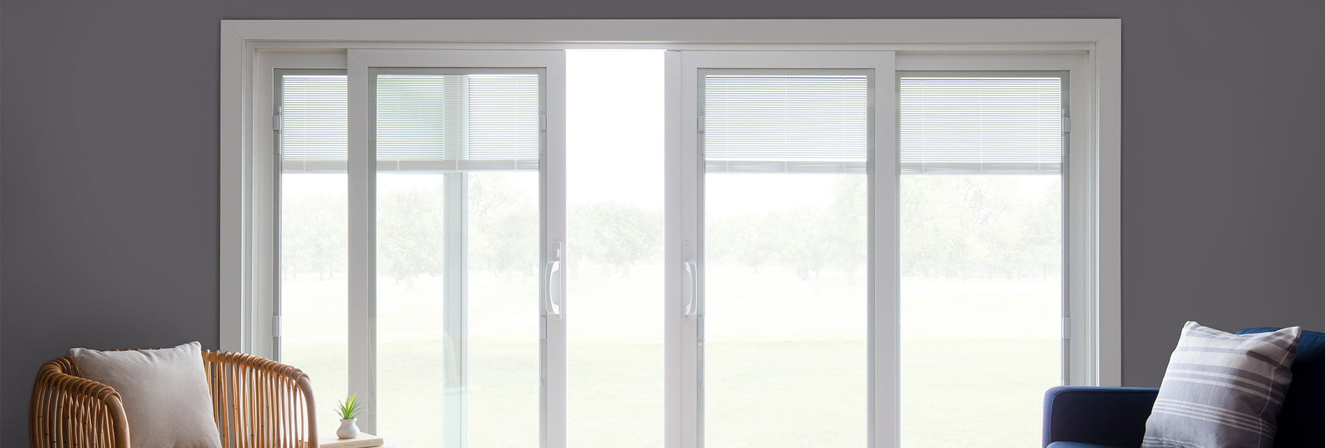 an expansive white sliding patio door with blinds-between-the-glass opens to a beautiful green backyard