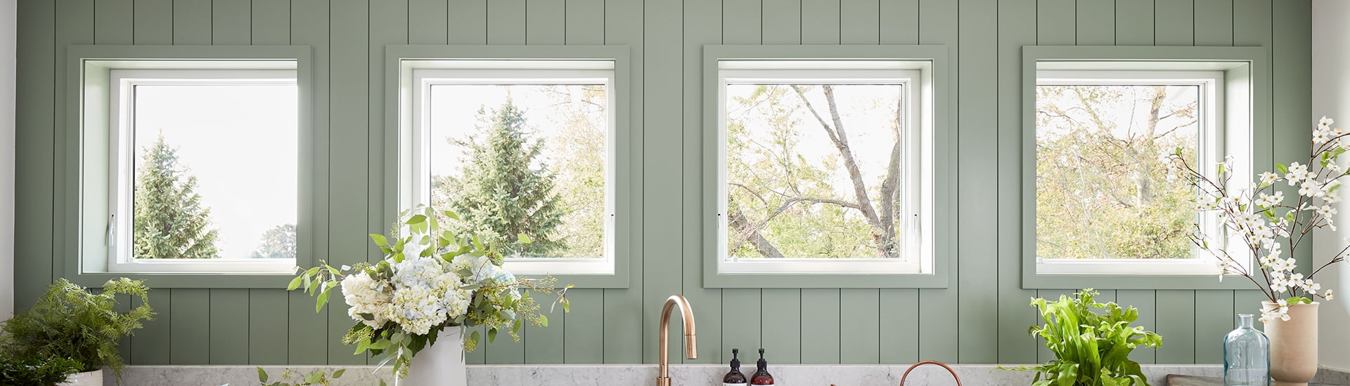 a three-season room surrounded by white double-hung windows highlighting a view of a lake nearby