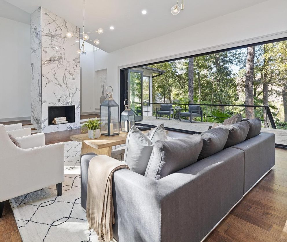 A modern living room features a black accordion glass door on the back wall, opening up to an outdoor deck.