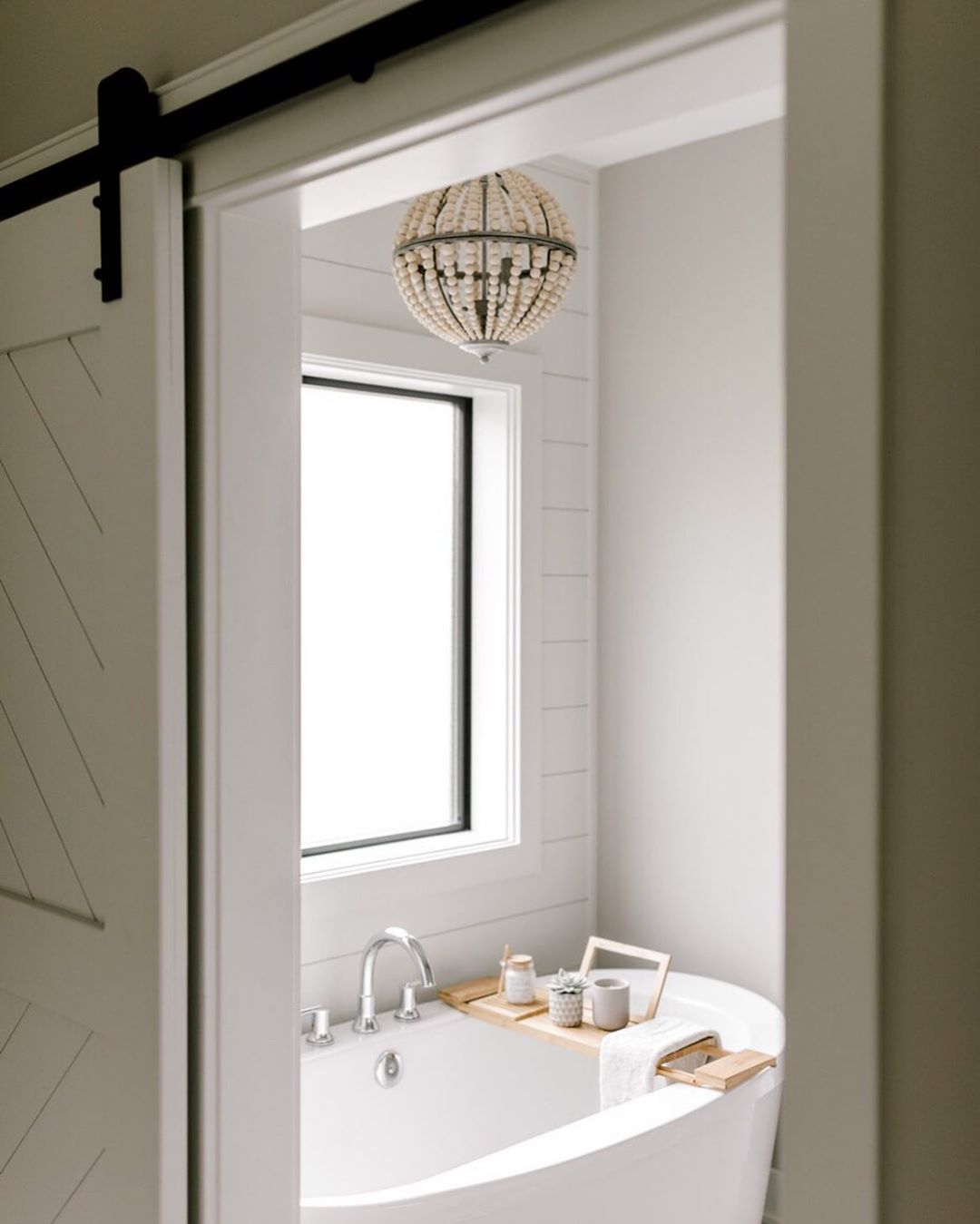 freestanding bathroom tub with chandelier and large fixed window