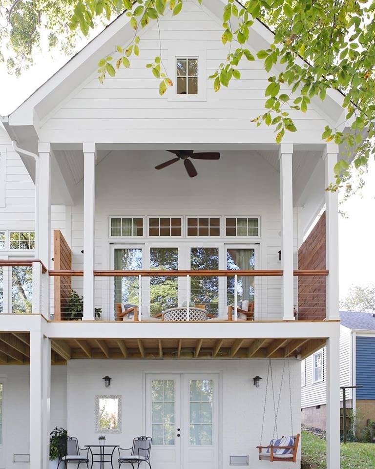 back of a white three story house with white sliding patio doors on the deck level and white french doors below