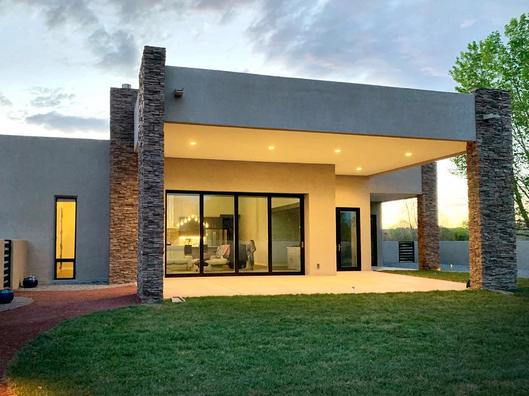 backyard of modern stone home with black sliding patio door