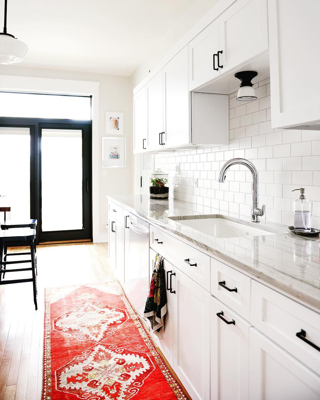 contemporary white kitchen with red rug and black patio door