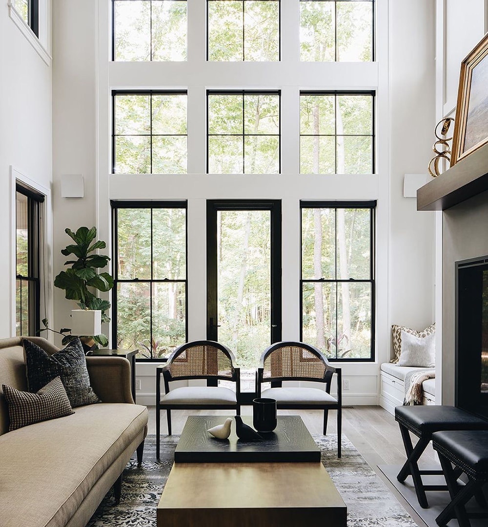 A modern contemporary living room features furniture up front with double-hung windows, picture windows and a patio door along the back wall.