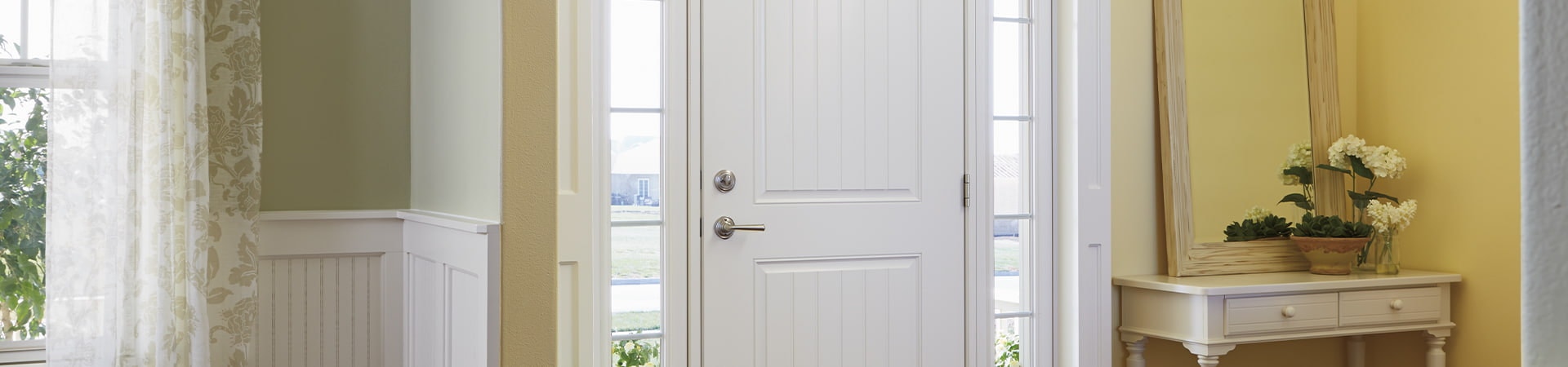 a traditional home interior with a two panel white front door and full light sidelights