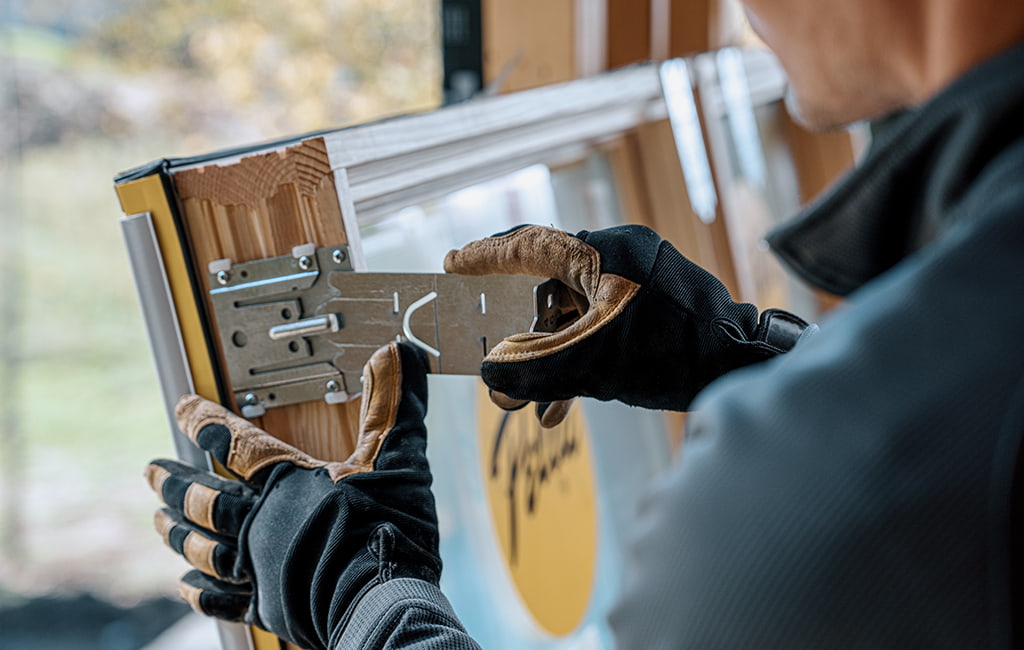 A black and white image of a female installer carrying a board in front of new Pella windows