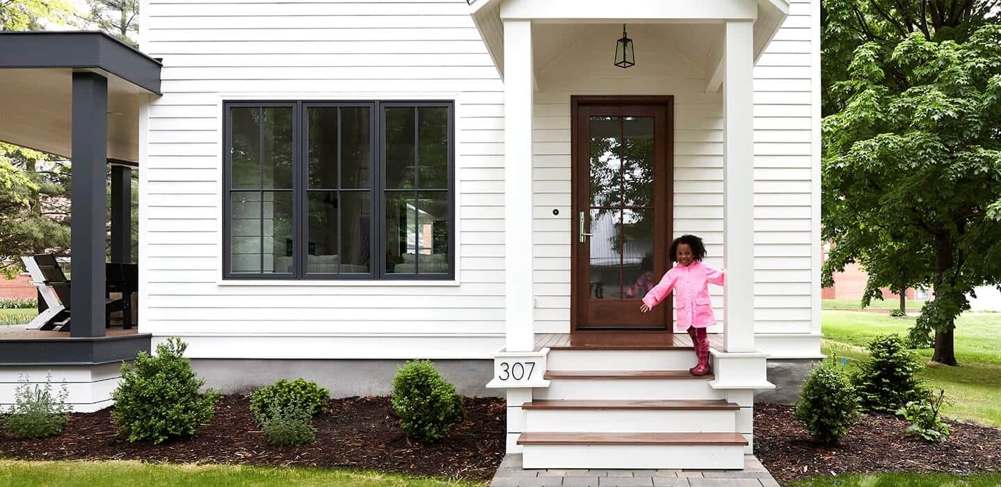 white exterior home small girl sitting on steps black trim