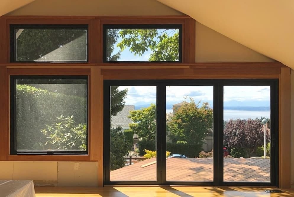 a wood bifold door sits to the right of a picture window and 2 awning windows