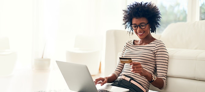 a woman sits on the floor with her laptop shopping for new windows